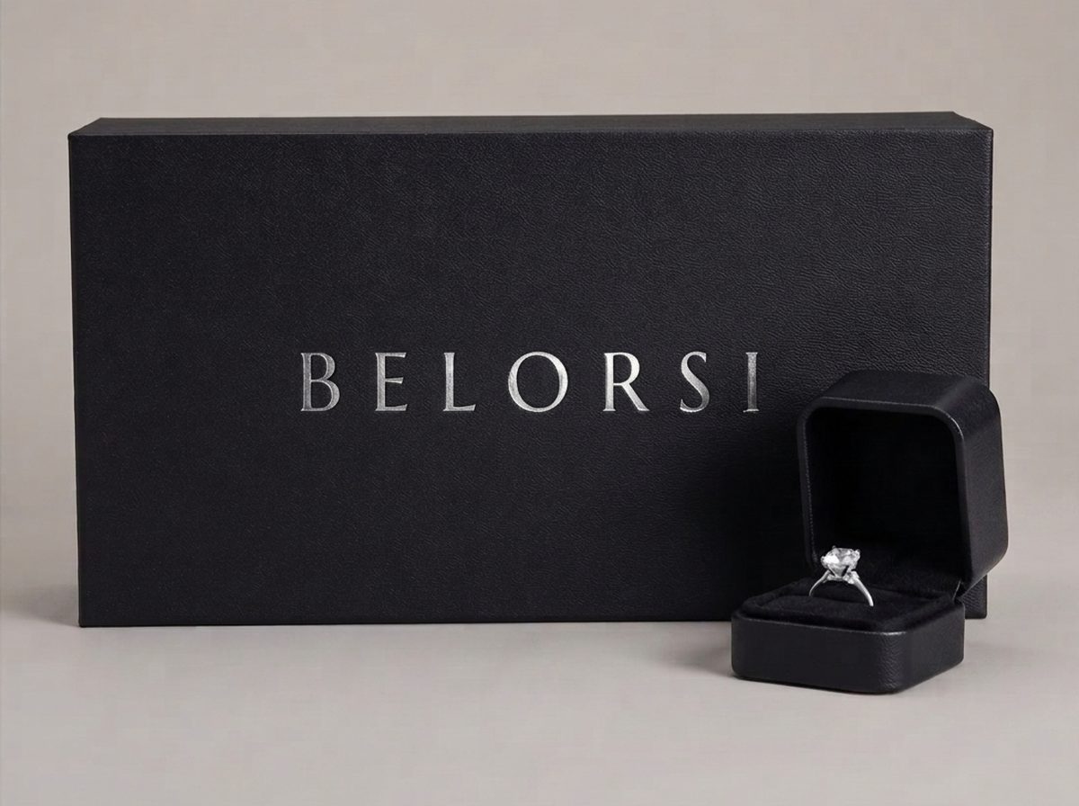 A Belorsi presentation box with a lab diamond solitaire ring in an open ring case beside it